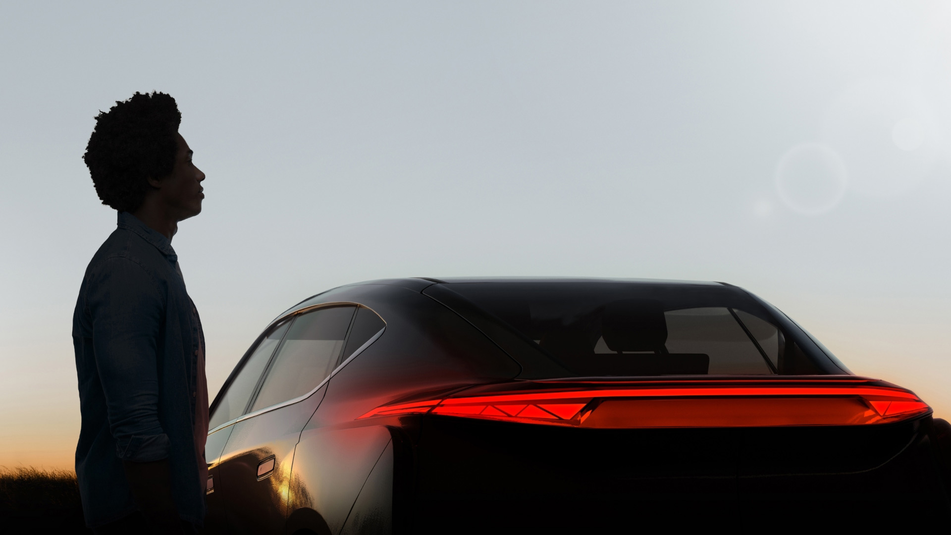 Person standing beside a car at sunset