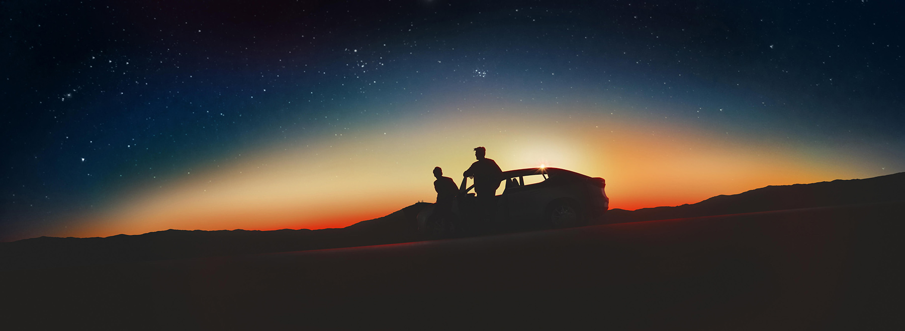 Silhouette of a vehicle with two people standing outside, sunset in the background