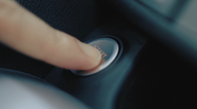 Close-up of a finger pressing a car engine start-stop button