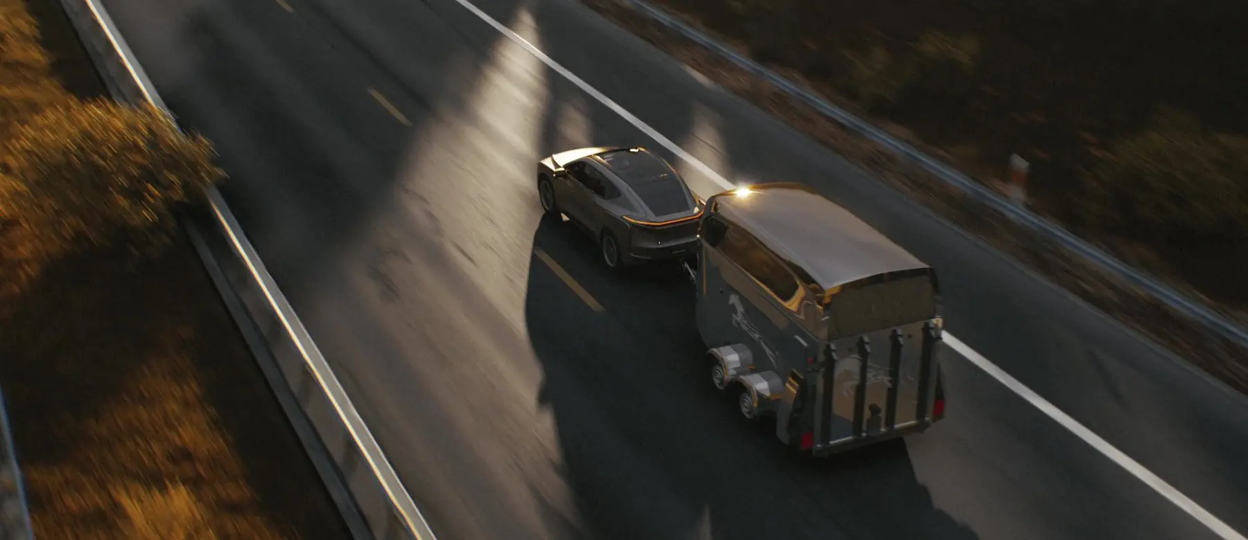 Car towing a trailer on a highway at sunset