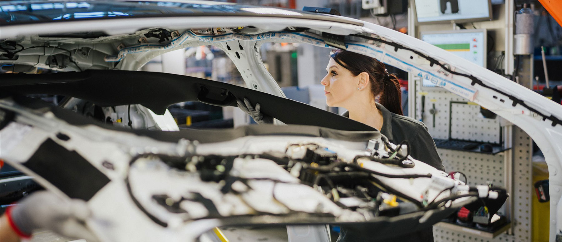 Worker assembling wiring inside a car body on an automotive production line