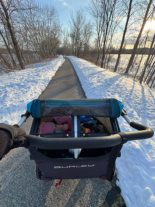 View from behind a stroller on a snowy path during a winter walk
