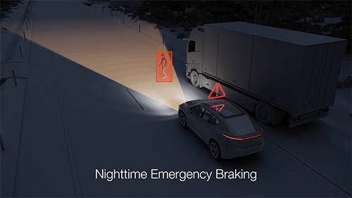 Animated vehicle driving along a dark road using nighttime emergency braking to detect person walking in front of the vehicle