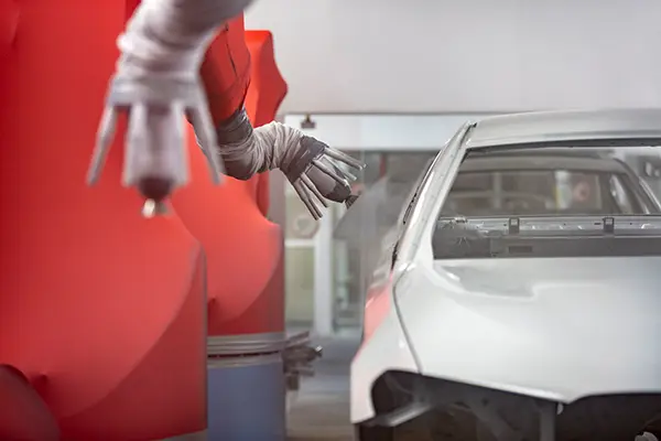 Robotic arm spray painting the body of a car on an assembly line